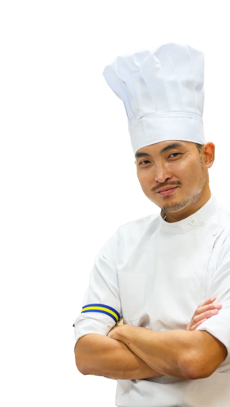 写真：腕を組んで微笑むシェフの男性。白いシェフ帽と制服を着用している。