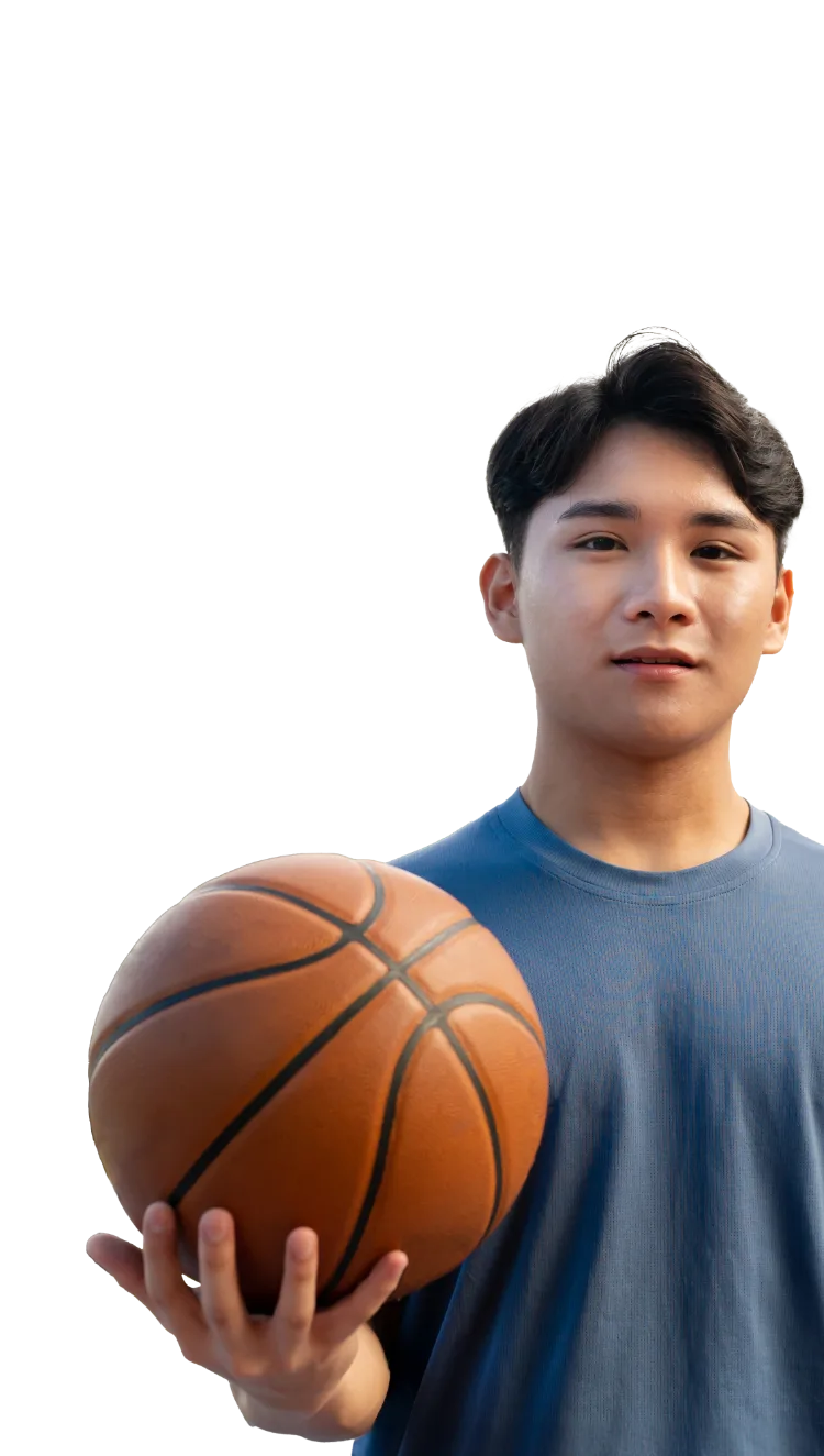 写真：バスケットボールを持つ青いTシャツを着た若いアジア人男性。真剣な表情で正面を向いている