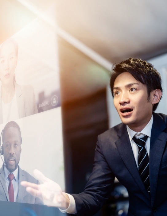 写真:男性がオンライン会議で複数の画面を見ながら話している。